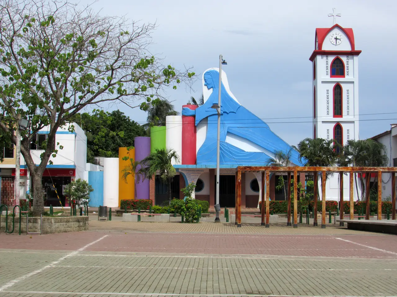 La plaza de Arboletes y su iglesia de colores, con una gran figura azul en la fachada y la torre blanca del reloj.